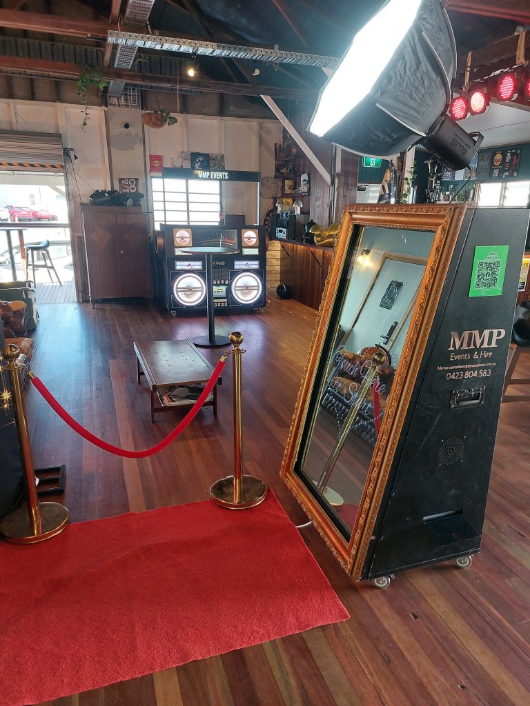 Memories Made and Personalised - Memories Made and Personalised - Ornate Gold-framed Mirror on a Wheeled Display Rack Beside a Red Carpet in a Retro Event Space Photo Booth Area with a Large Gold-framed Mirror, Red Rope Barrier, and Vintage Speaker Setup Interior of a Quirky Venue Showing a Gold-framed Mirror, a Red Carpet, and Stacked Sound Equipment Retro-themed Event Setup Featuring a Gold-framed Mirror, Rope Barrier, and Large Speaker Cabinet Wide View of a Studio with Ceiling Lights, Plants, and a Framed Mirror Next to a Booth -  - Photo Booth Hire | Packages & Pricing | Mmp Events -  - Photo Booth Hire | Packages & Pricing | Mmp Events